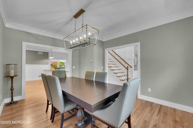 dining area with ornamental molding, light wood-type flooring, baseboards, and stairs