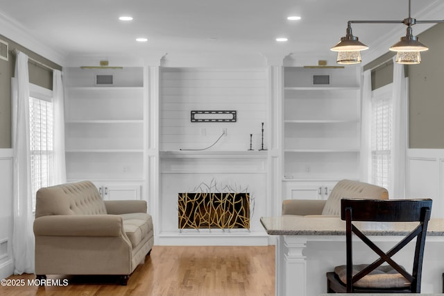 living area featuring built in features, visible vents, a fireplace, and light wood finished floors