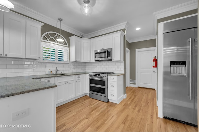 kitchen featuring stainless steel appliances, ornamental molding, a sink, and white cabinets