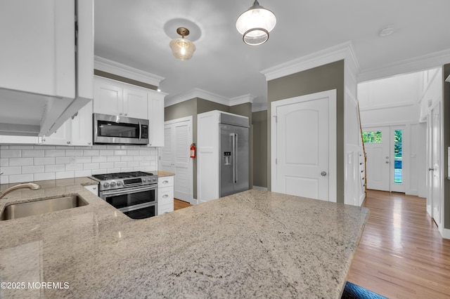 kitchen featuring tasteful backsplash, light wood-style flooring, appliances with stainless steel finishes, ornamental molding, and light stone countertops