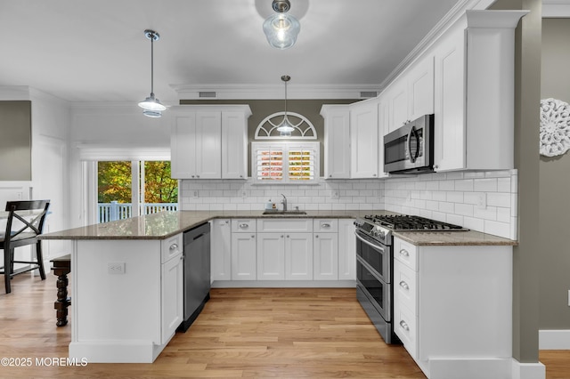 kitchen with a peninsula, white cabinetry, stainless steel appliances, and crown molding