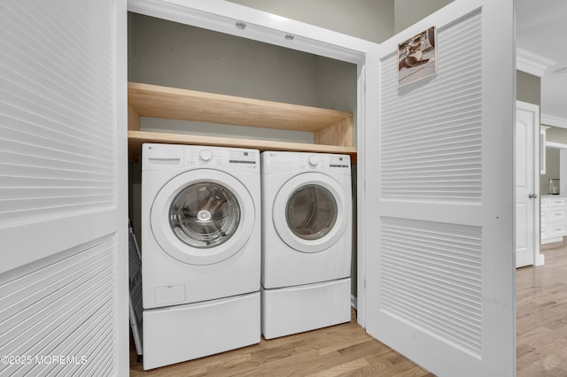 laundry area with laundry area, washer and clothes dryer, and light wood-type flooring