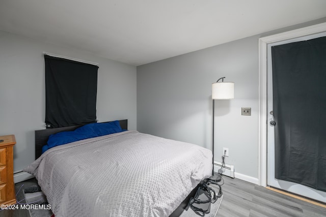 bedroom featuring baseboards, baseboard heating, and wood finished floors