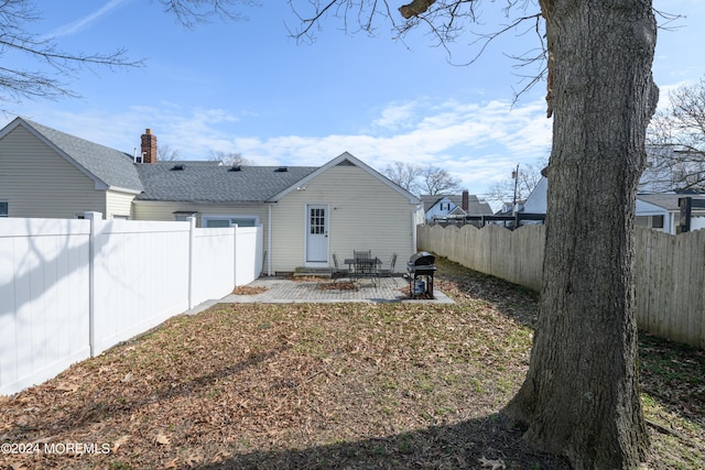 rear view of house featuring a patio area, a fenced backyard, and roof with shingles