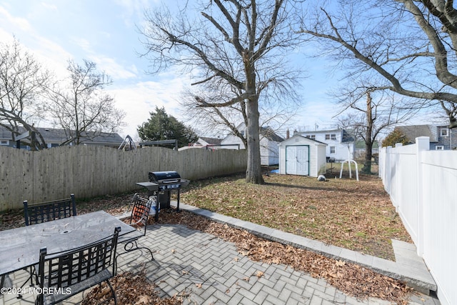 view of patio featuring an outbuilding, outdoor dining area, a storage unit, area for grilling, and a fenced backyard