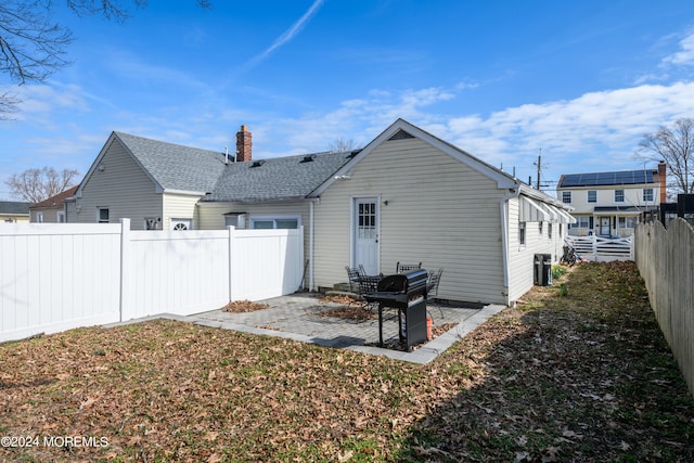 rear view of house featuring a chimney, a patio area, a fenced backyard, and roof with shingles