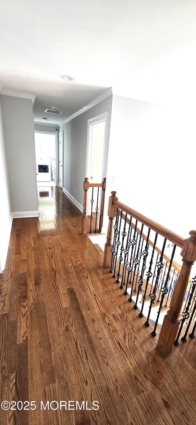 hall featuring an upstairs landing, baseboards, crown molding, and wood finished floors