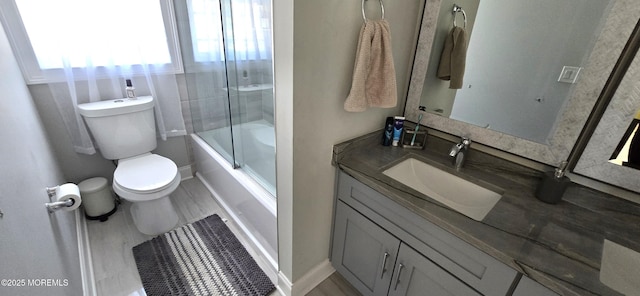 bathroom with toilet, baseboards, bath / shower combo with glass door, and vanity