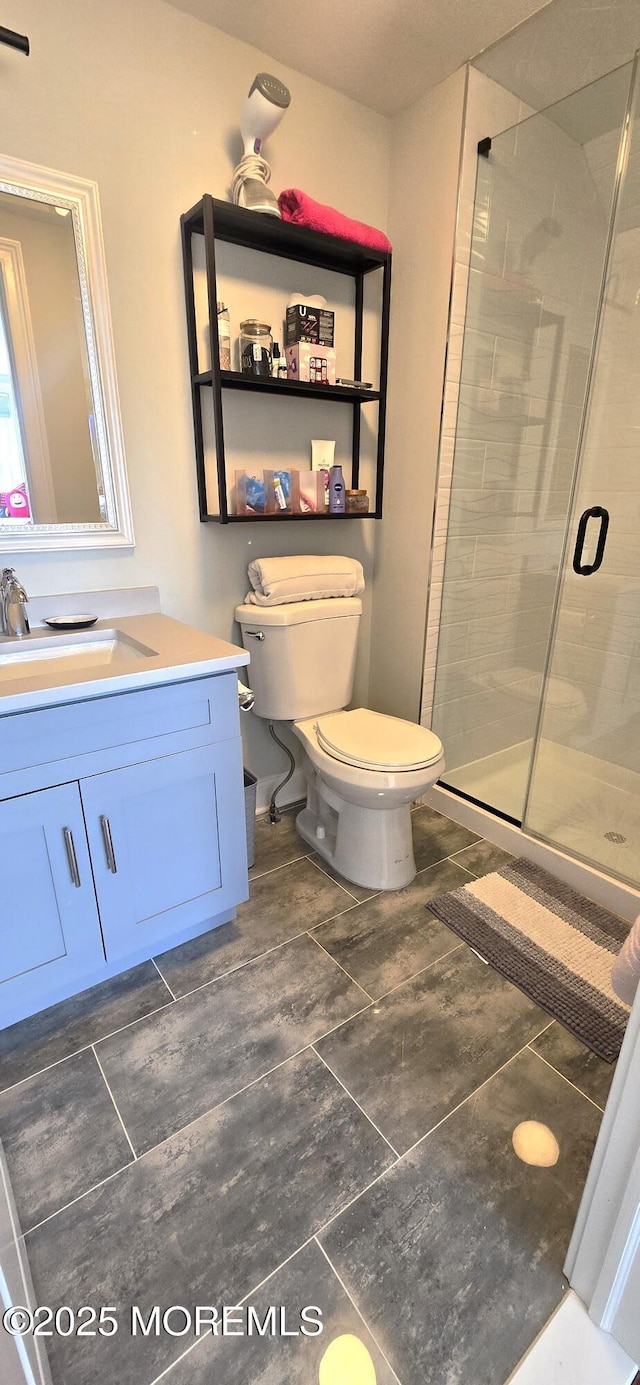 bathroom featuring toilet, a stall shower, and vanity