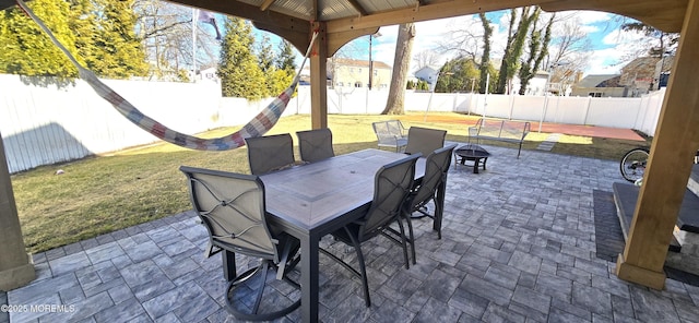 view of patio with outdoor dining area, a fenced backyard, and a fire pit