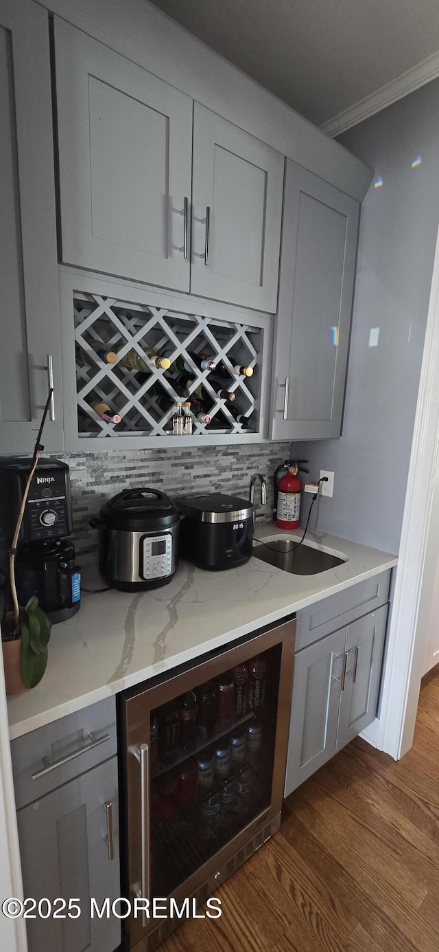 bar with beverage cooler, a bar, a sink, and crown molding