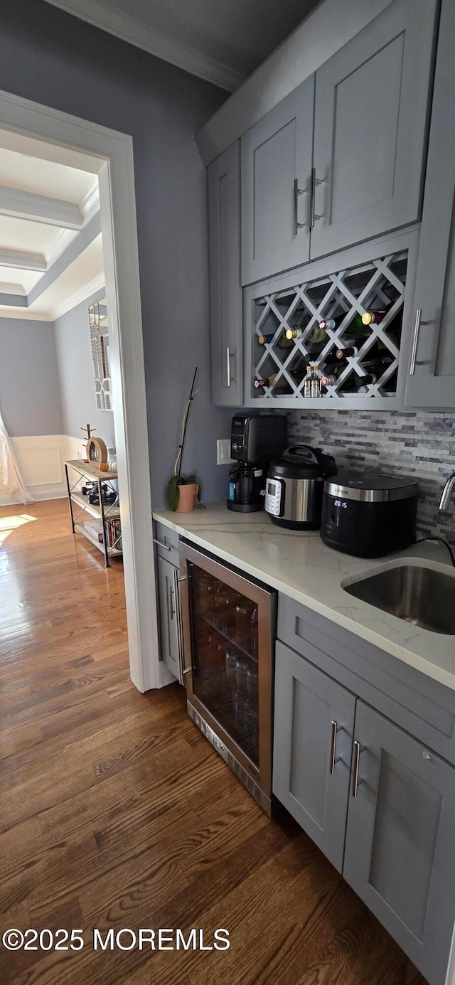 bar featuring dark wood-style floors, crown molding, a dry bar, a sink, and beverage cooler