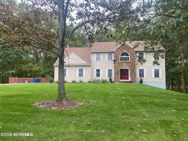 colonial inspired home featuring stone siding and a front yard