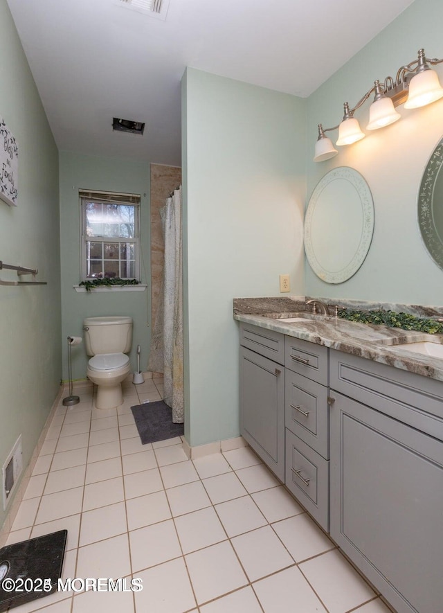 bathroom featuring visible vents, toilet, double vanity, tile patterned floors, and a sink