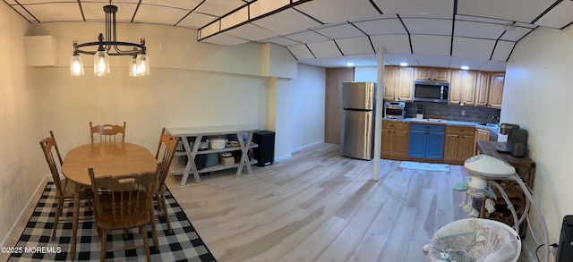 kitchen featuring light wood-style floors, baseboards, backsplash, and stainless steel appliances