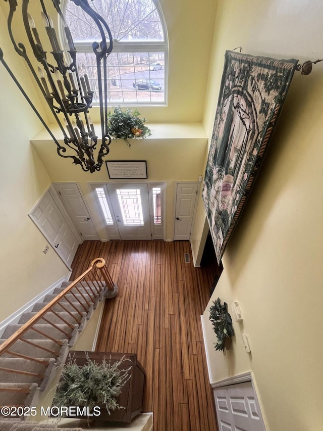 foyer entrance with stairway, a towering ceiling, baseboards, and wood finished floors