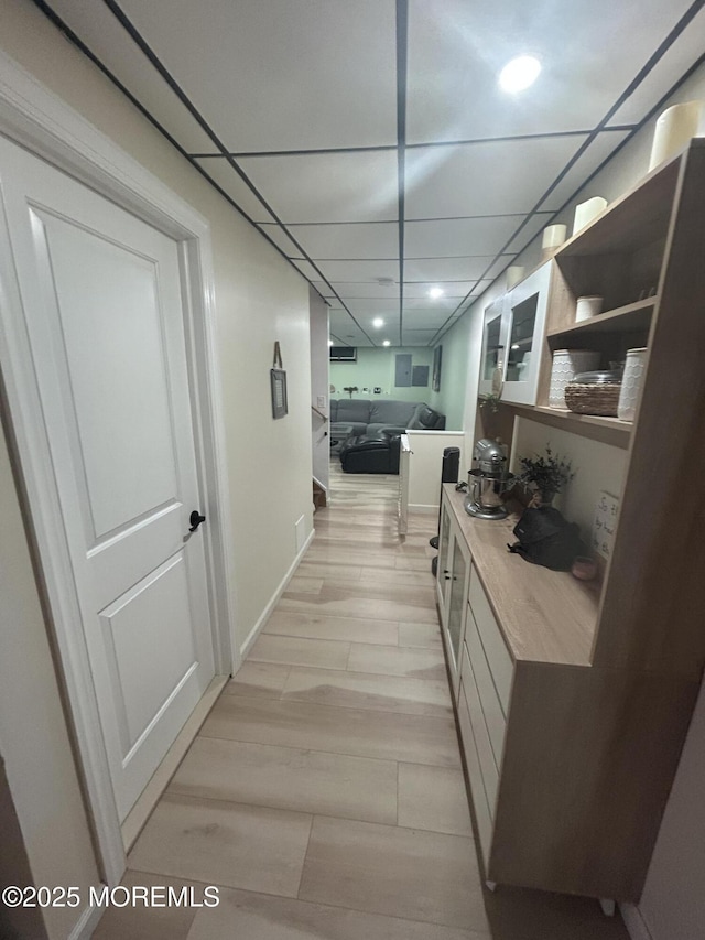 hallway with light wood-type flooring and a paneled ceiling