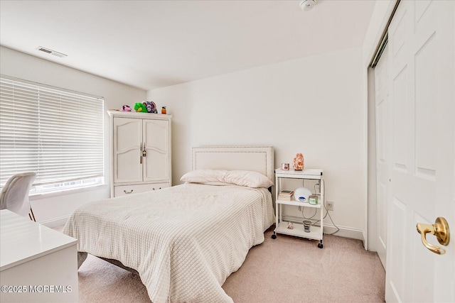 bedroom featuring baseboards, visible vents, light carpet, and a closet