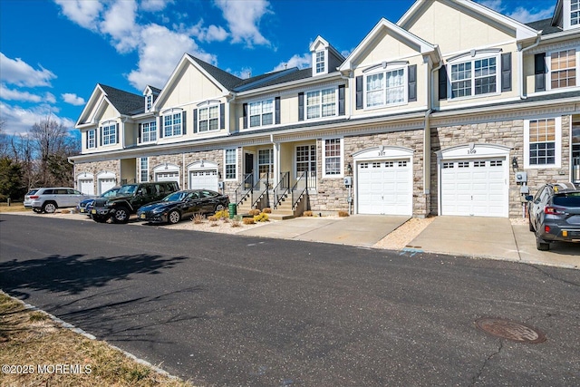 townhome / multi-family property featuring a garage, stone siding, board and batten siding, and driveway