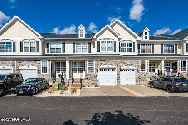 townhome / multi-family property with stone siding and driveway