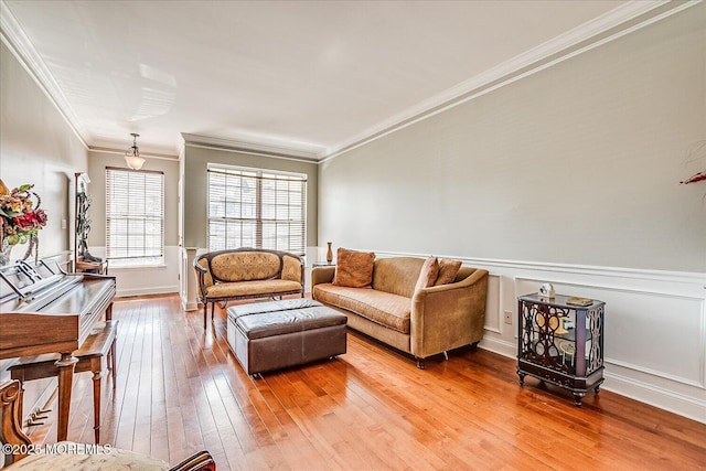 living room featuring light wood finished floors, a wainscoted wall, and crown molding