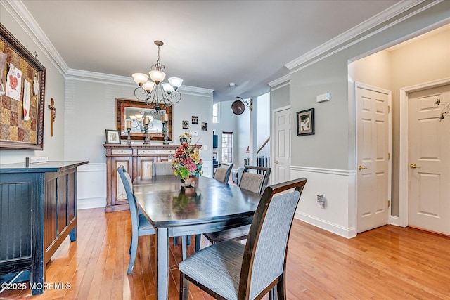 dining area featuring a chandelier, wainscoting, light wood-style flooring, and crown molding