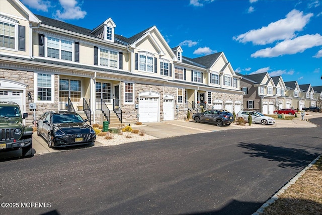 multi unit property with stone siding, a garage, and a residential view