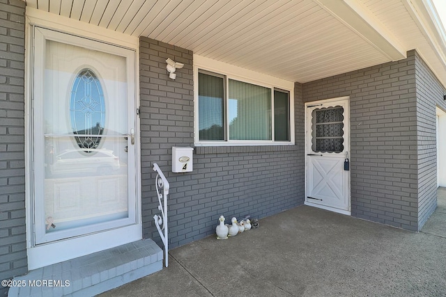 property entrance featuring brick siding and covered porch