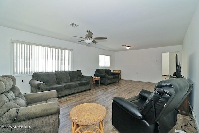 living room with light wood-style flooring, visible vents, and ceiling fan