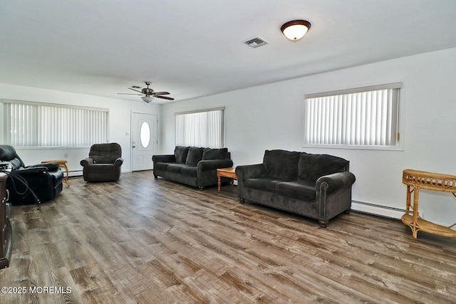 living room featuring ceiling fan, visible vents, baseboard heating, and wood finished floors