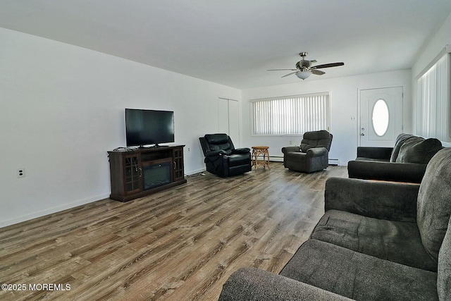 living room featuring baseboard heating, baseboards, and wood finished floors