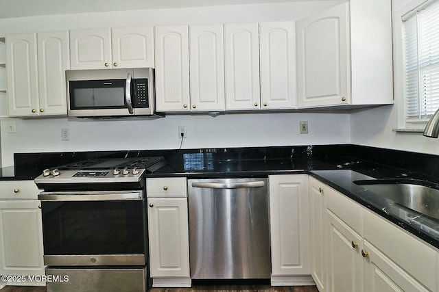 kitchen with dark countertops, white cabinetry, and stainless steel appliances