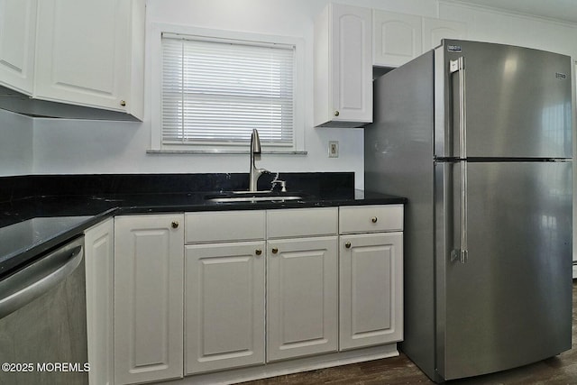 kitchen featuring white cabinetry, dark countertops, appliances with stainless steel finishes, and a sink