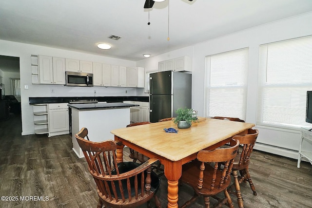 kitchen with stainless steel microwave, a healthy amount of sunlight, dark wood-style flooring, and freestanding refrigerator