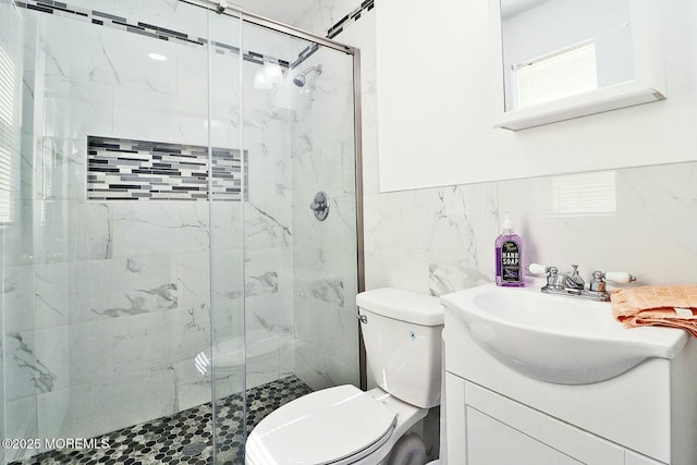 full bath featuring vanity, tile walls, toilet, and a marble finish shower