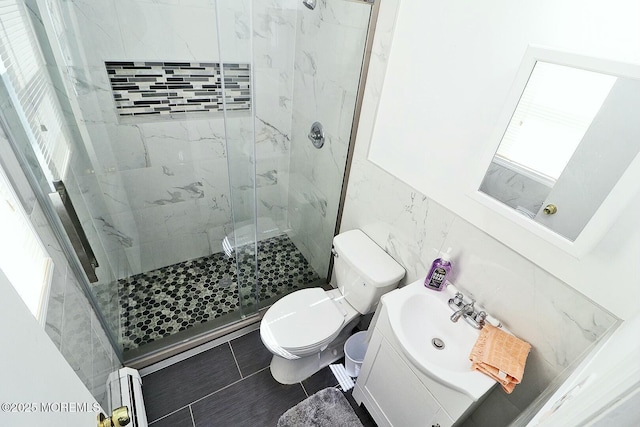 bathroom with a marble finish shower, toilet, vanity, tile walls, and a baseboard radiator