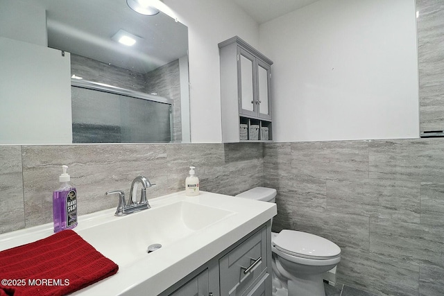 full bathroom with tile walls, a shower stall, toilet, and vanity