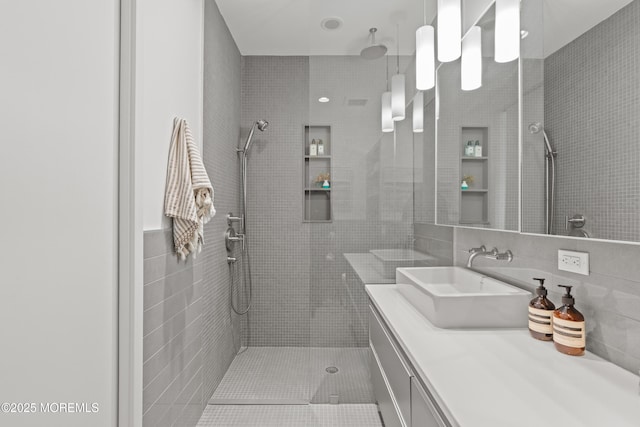 bathroom featuring tile walls, tiled shower, and vanity