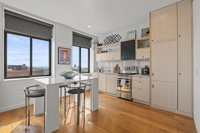 kitchen with open shelves, stainless steel range with gas stovetop, light wood finished floors, and light countertops