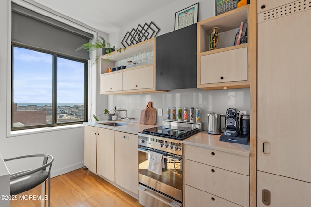 kitchen with open shelves, a sink, light countertops, stainless steel range with electric stovetop, and light wood-style floors