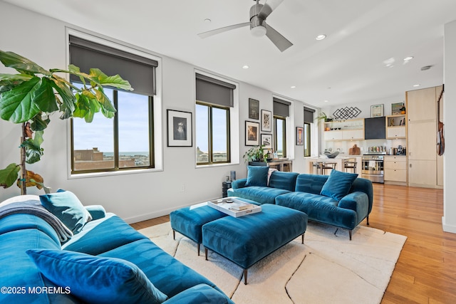 living area with a ceiling fan, light wood-style flooring, recessed lighting, and baseboards