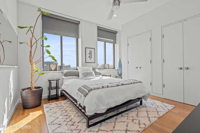 bedroom with recessed lighting, wood finished floors, two closets, and ceiling fan