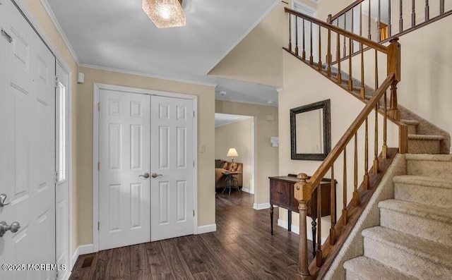 foyer entrance featuring dark wood finished floors, crown molding, stairway, and baseboards