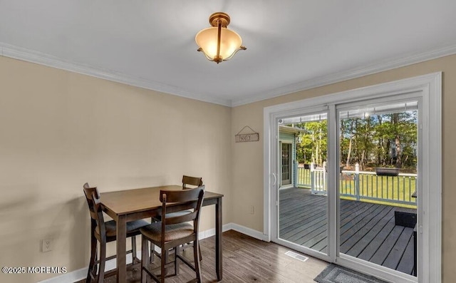 dining area featuring visible vents, wood finished floors, baseboards, and ornamental molding