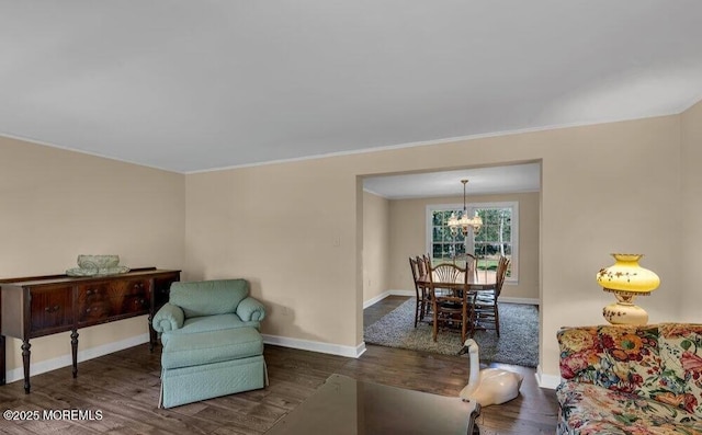 sitting room featuring baseboards, an inviting chandelier, wood finished floors, and ornamental molding