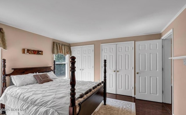 bedroom with ornamental molding, two closets, and wood finished floors