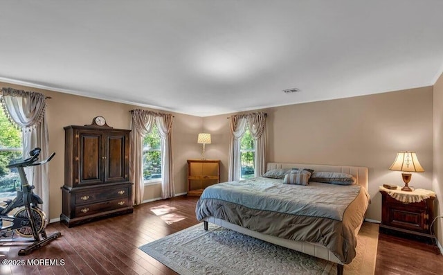 bedroom with visible vents, baseboards, hardwood / wood-style floors, and crown molding