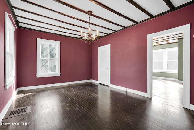 empty room featuring a chandelier, hardwood / wood-style floors, visible vents, and baseboards