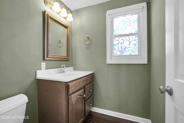 bathroom featuring toilet, baseboards, wood finished floors, and vanity