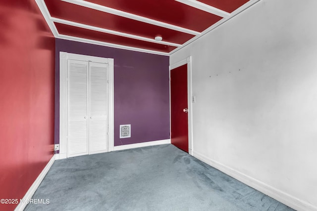 unfurnished room featuring carpet, beam ceiling, visible vents, and baseboards